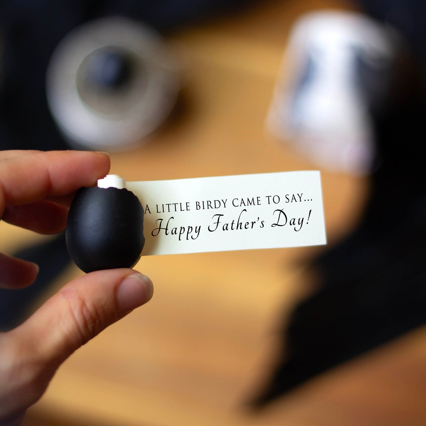 A black egg with a note scroll coming out of it which reads "A little birdy came to say...Happy Father's Day!"