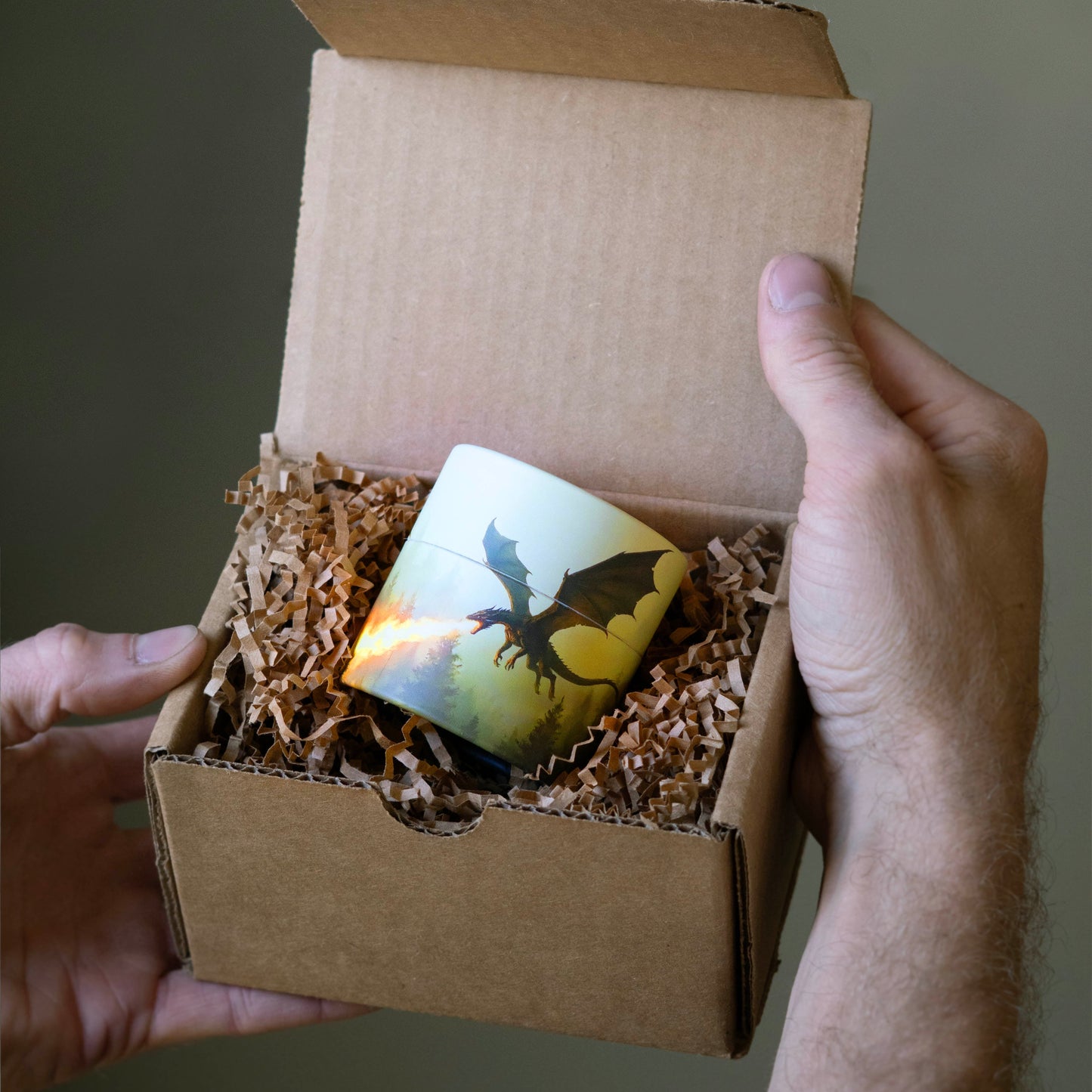 Person holding a small cardboard box with a dragon-themed card inside