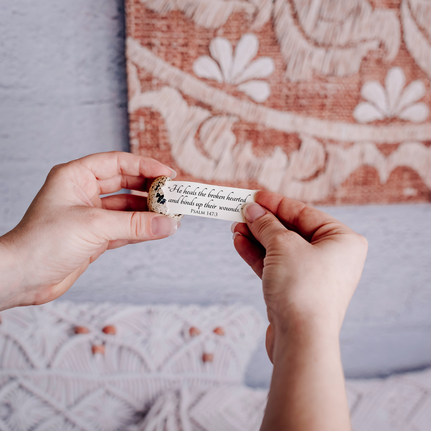 Two hands holding a small card being pulled out of an egg that reads "“He heals the broken hearted
and binds up their  wounds.”
Psalm 147:3