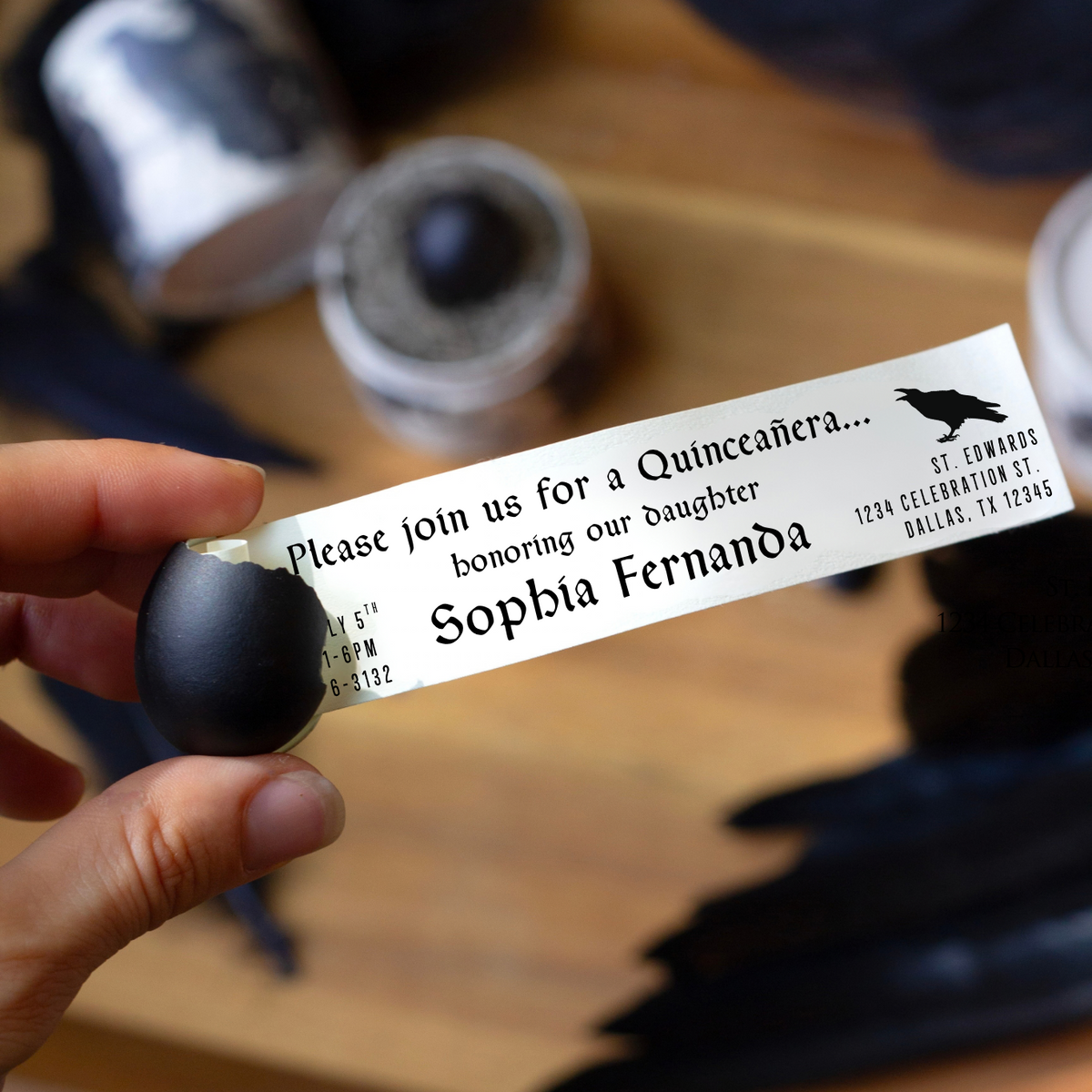 A hand holds a small, black egg, which is cracked open to reveal a secret message. The Message is a quinceanera invitation note. 