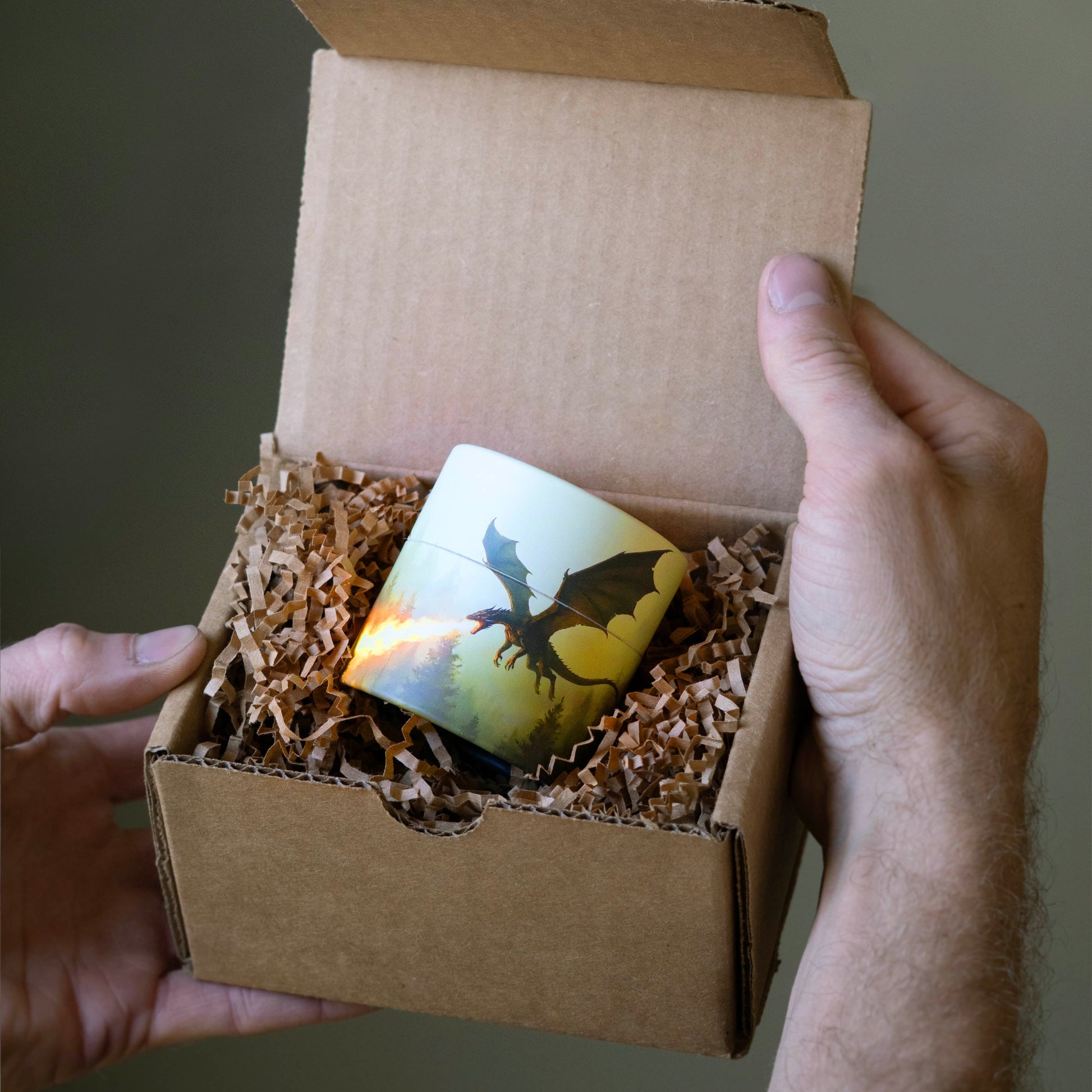 Person holding a small cardboard box with a dragon-themed card inside